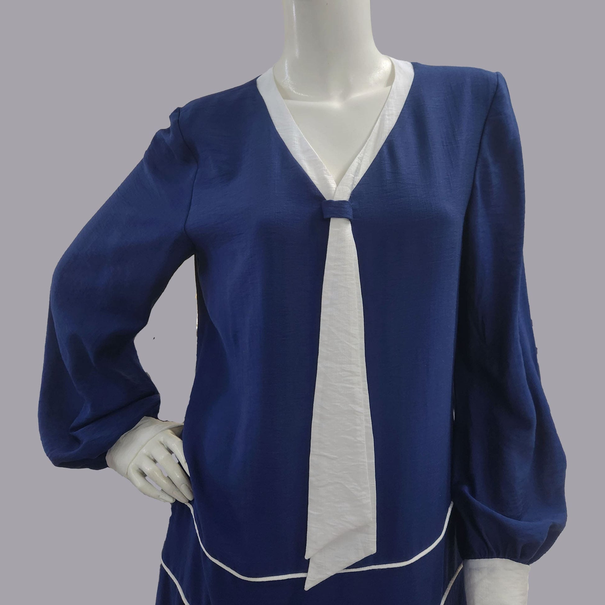 Blue blouse with white accents on a mannequin against a gray background
