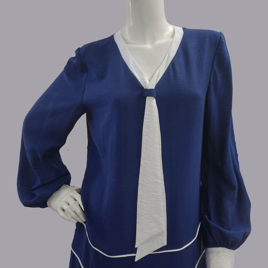 Blue blouse with white accents on a mannequin against a gray background