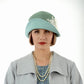 A 1920s-inspired linen cloche hat in muted green and pastel blue that matches some of our Great Gatsby coats. 